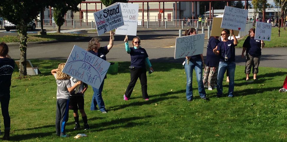 Picketers hold signs: We stand behind classified staff