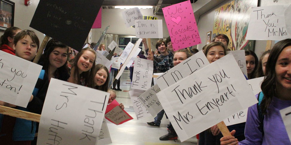 Students line both sides of a school hallway with "Thank You" signs.